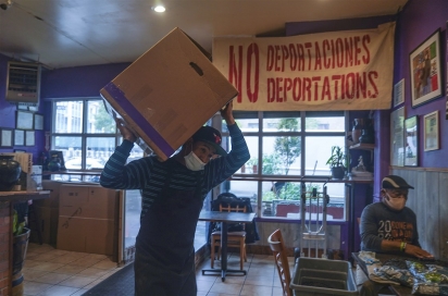 Um trabalhador levanta uma caixa contendo refeições preparadas no La Morada. (Foto: Associated Press/Bebeto Matthews)