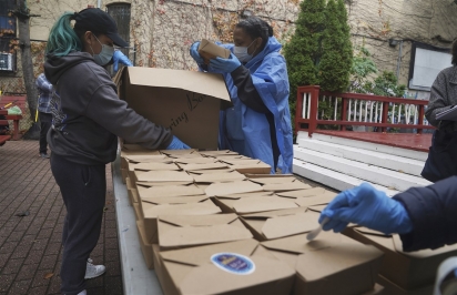 Voluntários descarregam refeições embaladas preparadas no restaurante La Morada. (Foto: Associated Press/Bebeto Matthews)