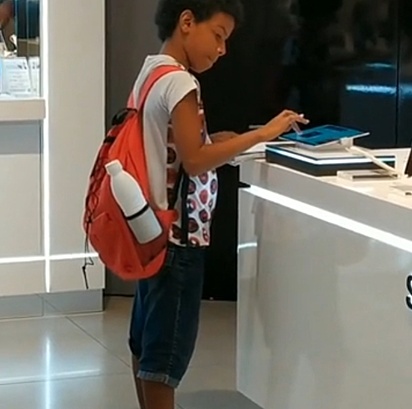 O menino estudando em tablet de loja.