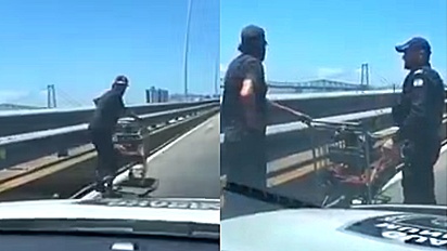 Polícia ajuda homem morador de rua a atravessar ponte movimentada em Florianópolis.